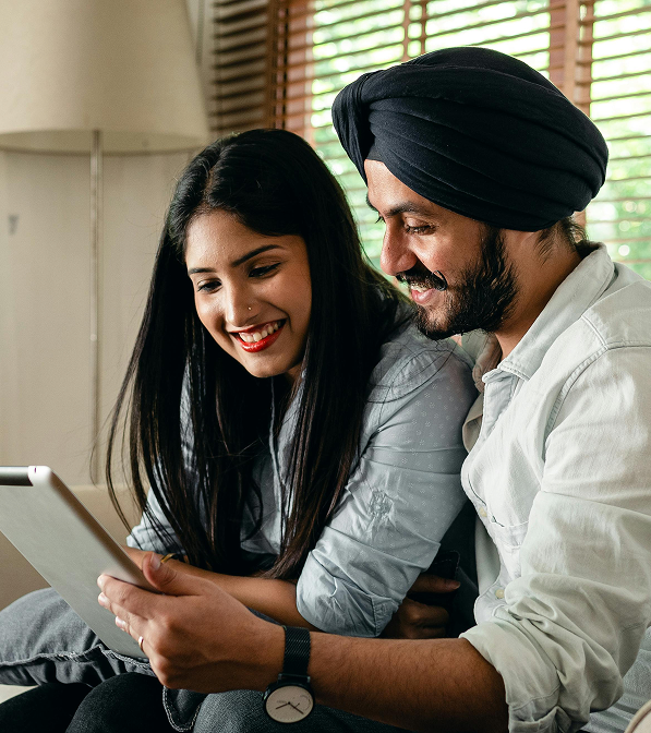 Couple smiling and reviewing mortgage information together on a tablet