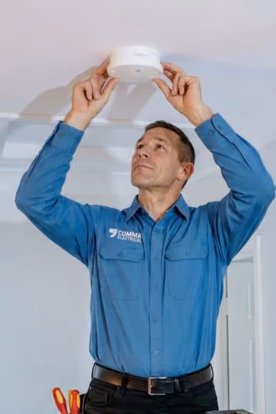 Comma Electrical electrician servicing a smoke alarm in a Brisbane Home