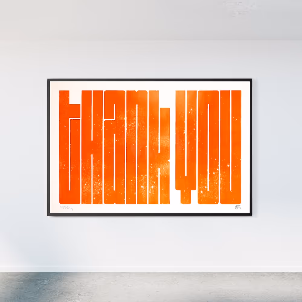 A large print featuring the words 'Thank you' in bright orange ink, framed and hung on a wall