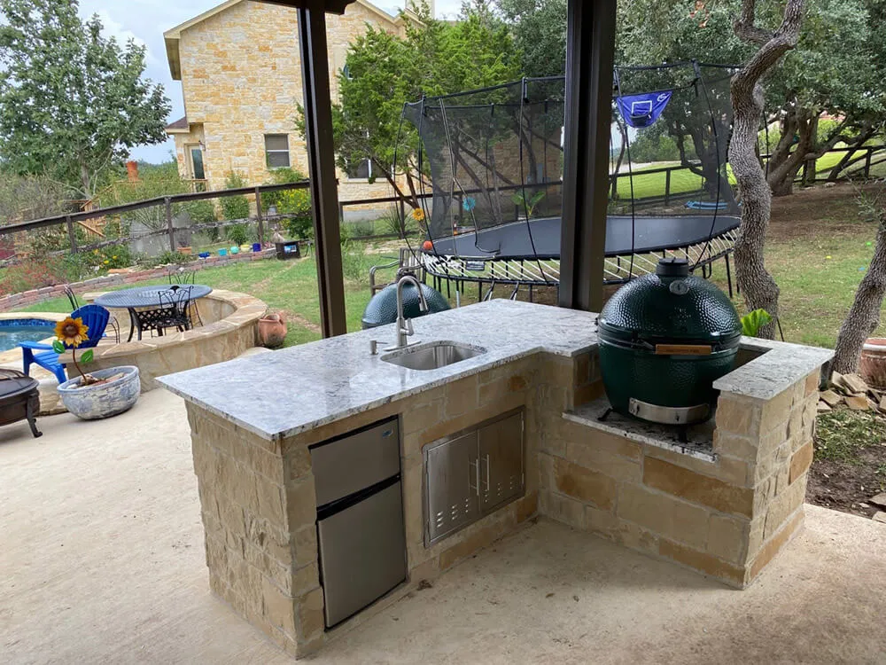 small outdoor kitchen with trampoline in background
