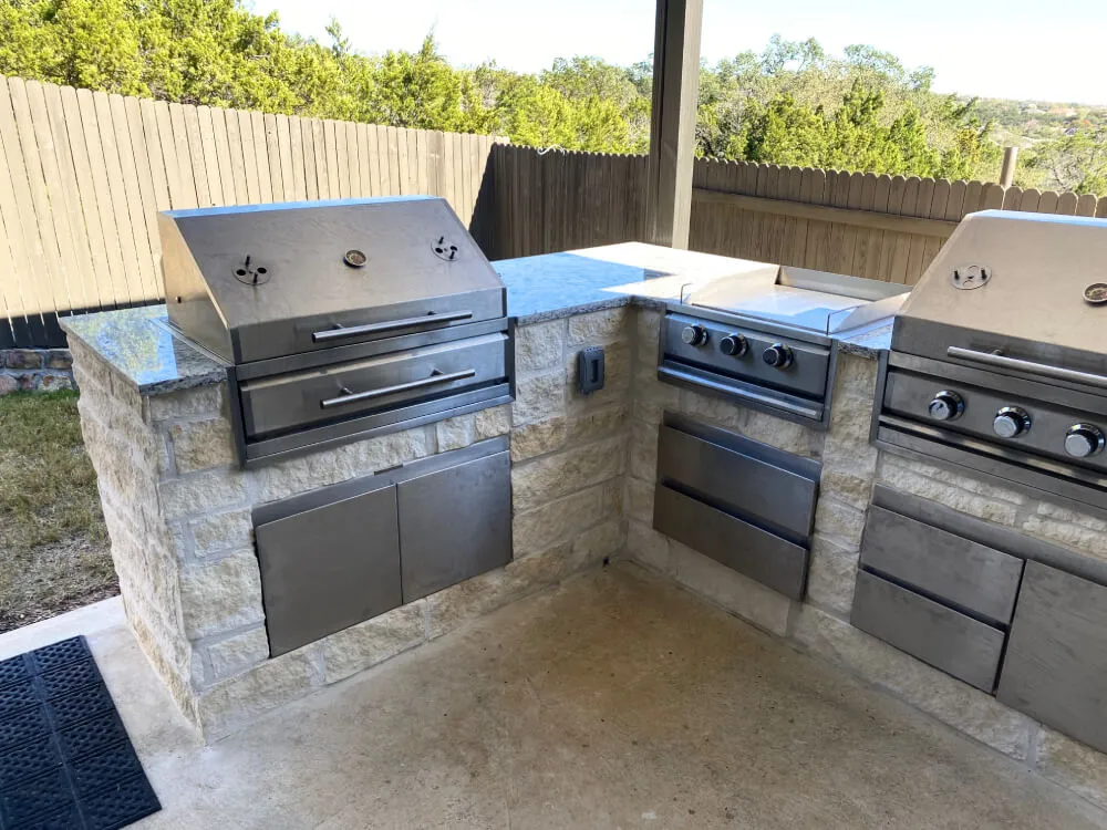 Outdoor kitchen with stone base, stainless steel appliances, grill, open patio, San Antonio.