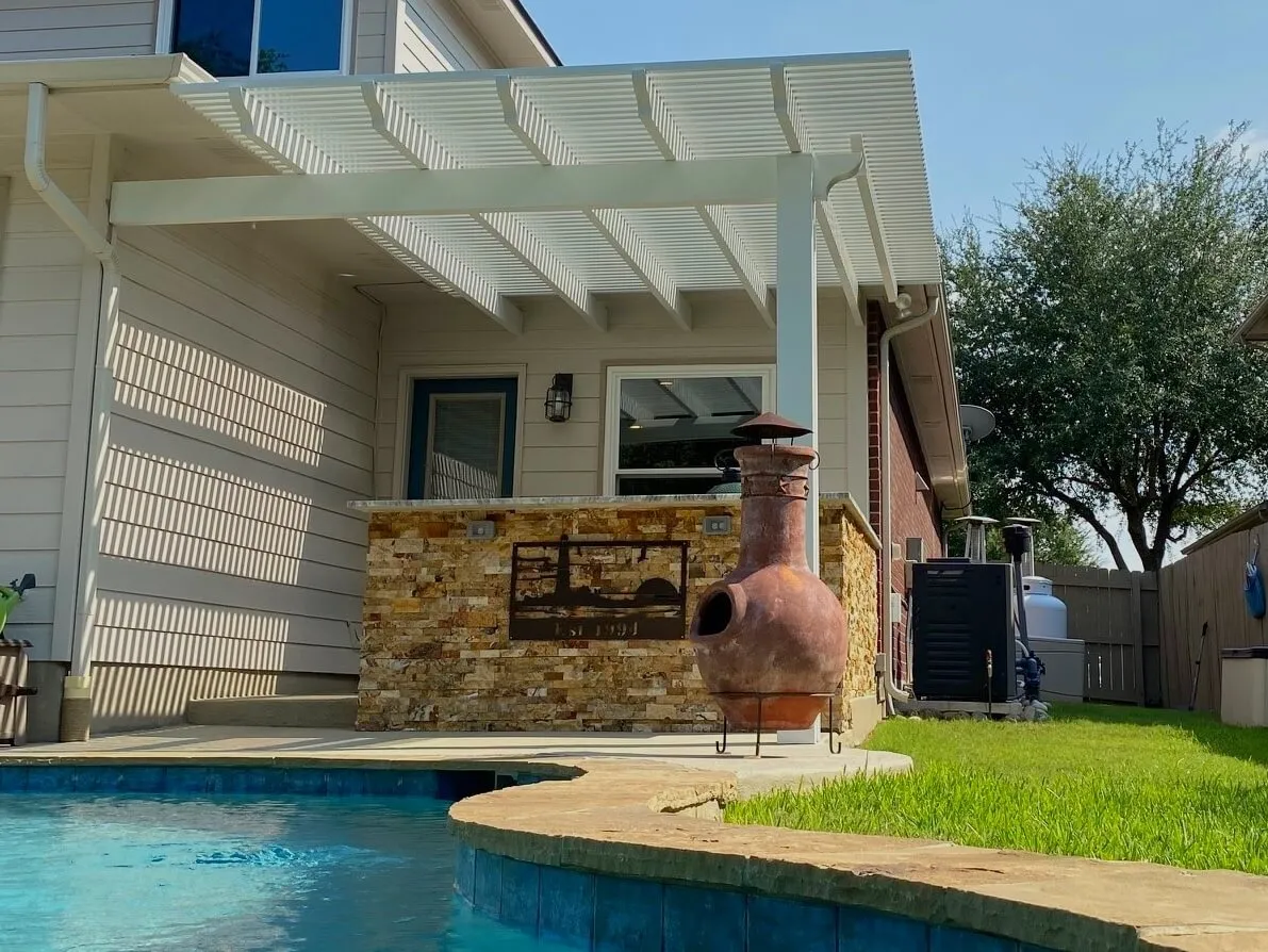 white pergola adjacent to mud red fireplace