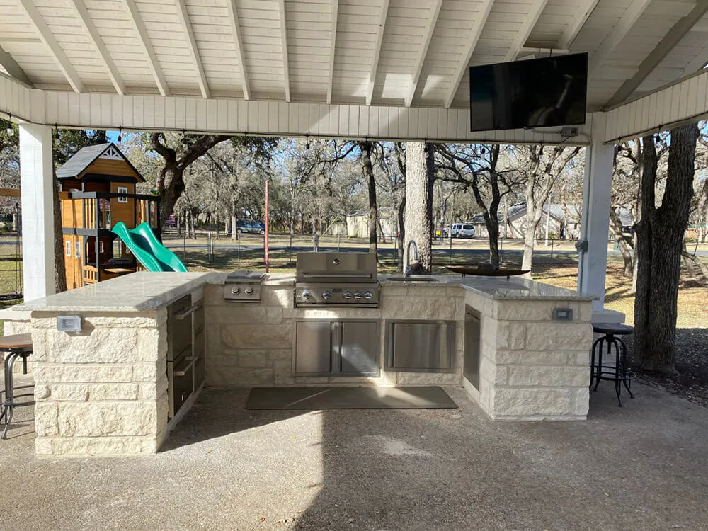 white outdoor kitchen with tv and stainless steel grill