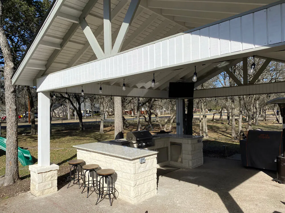 outdoor kitchen below huge white patio cover