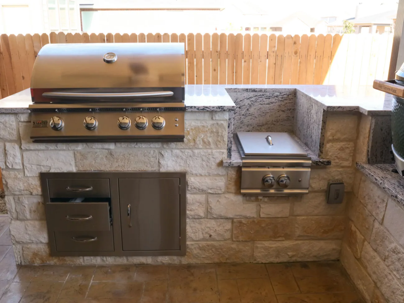 Outdoor kitchen with grill and granite countertop.