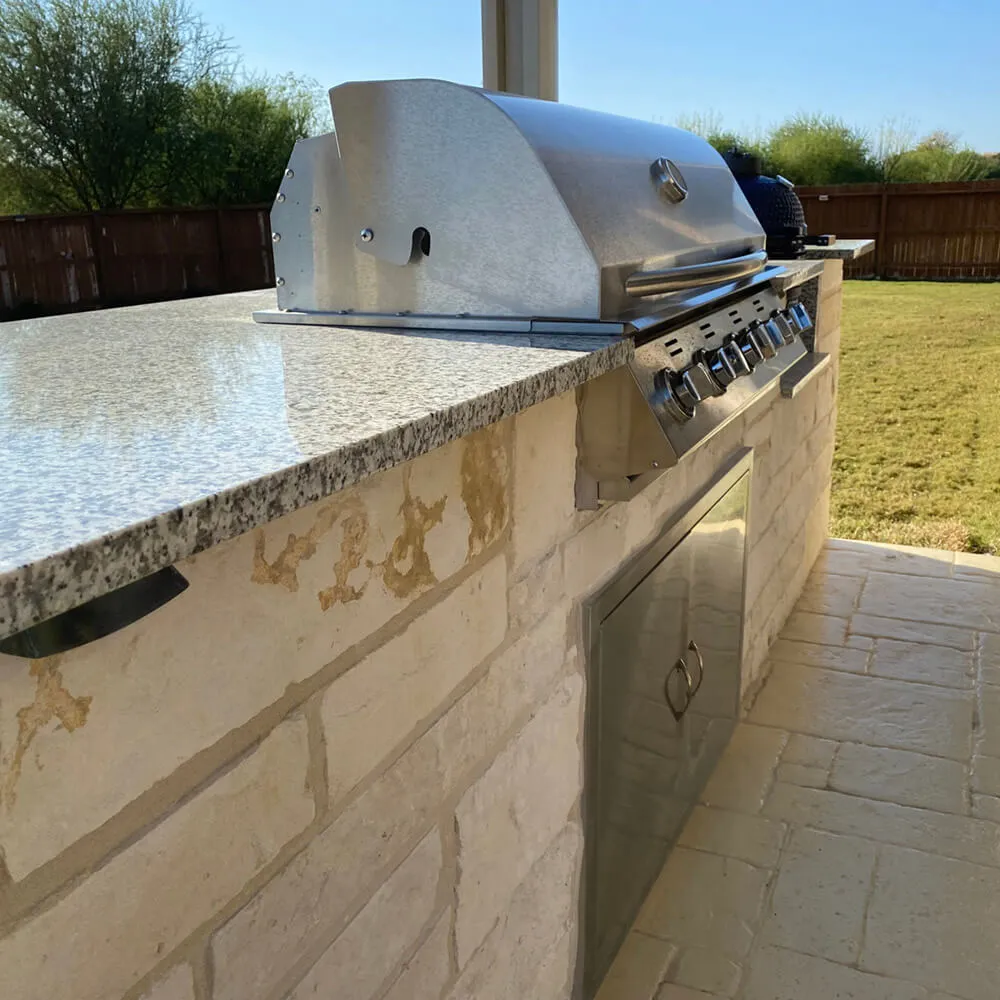 outdoor kitchen with stainless steel grill and marble table