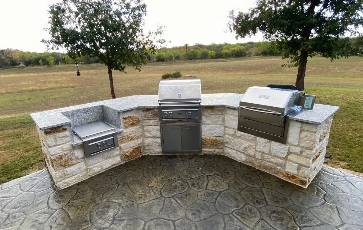 Outdoor kitchen with grill and stone countertop.