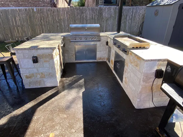 Outdoor kitchen with grill and stone countertops.
