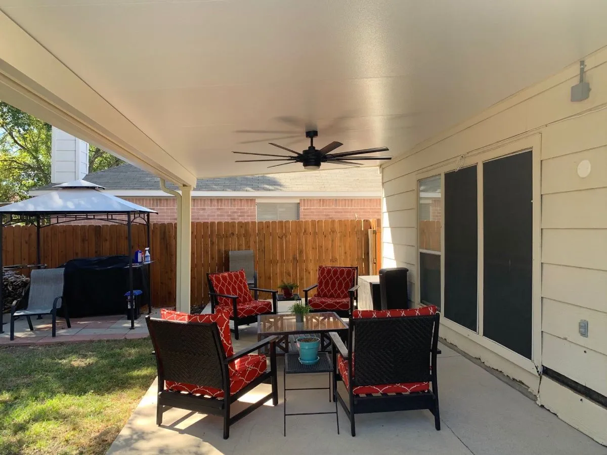 Covered patio with red cushioned chairs in San Antonio backyard.