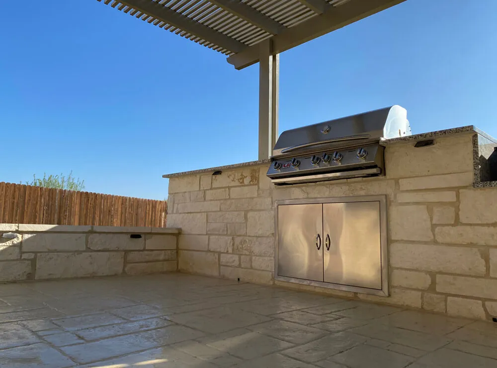 outdoor kitchen with silver grill and concrete siding