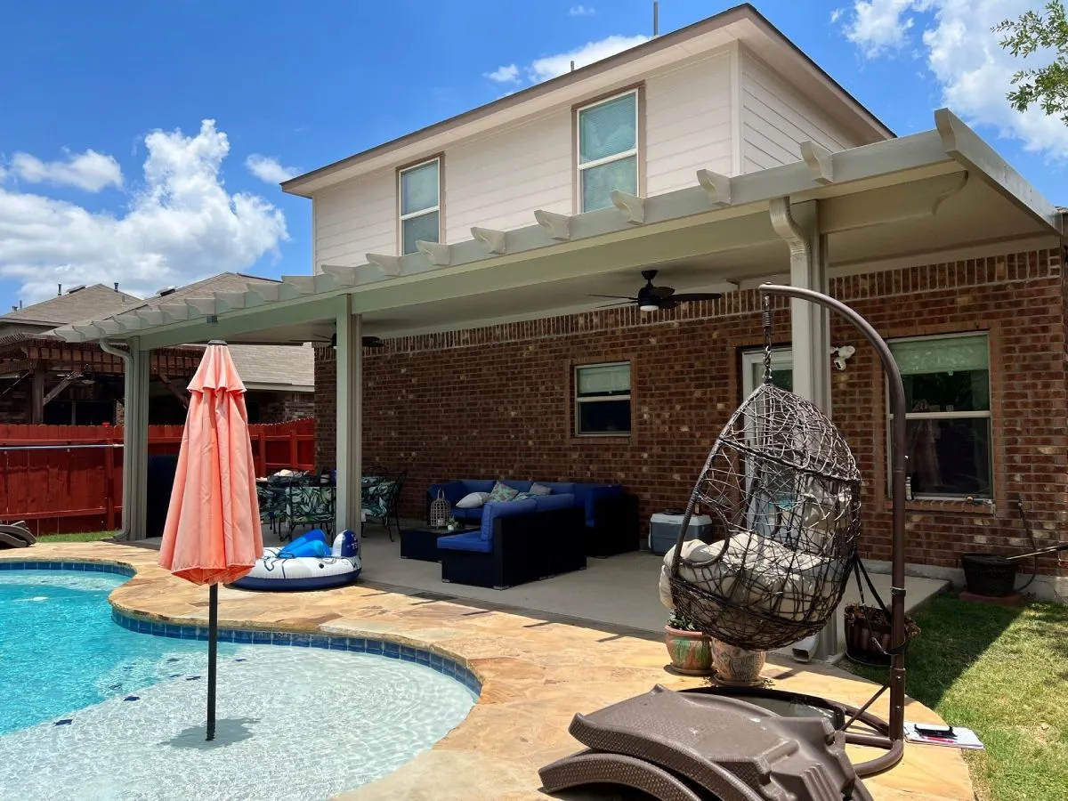Patio with pergola, sofa set, pool, and hanging chair in San Antonio backyard.