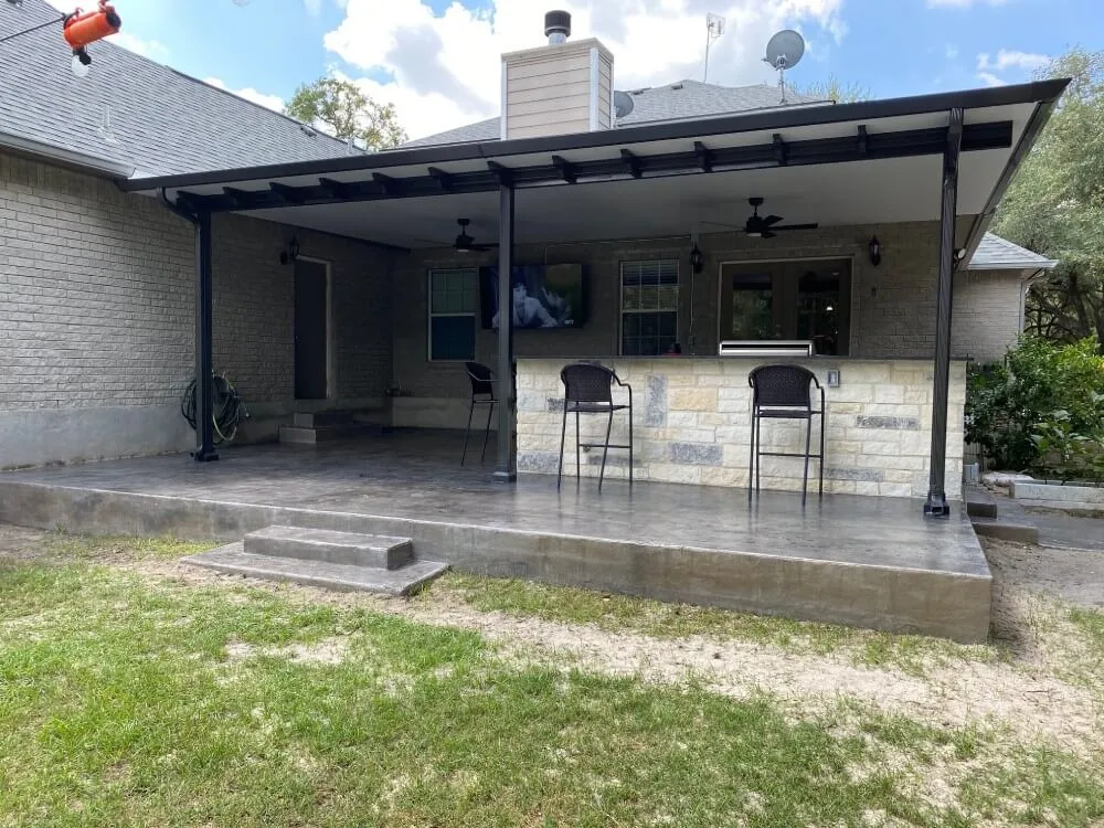 Covered patio with bar stools and brick house