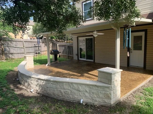 Covered patio with stone wall in San Antonio backyard.