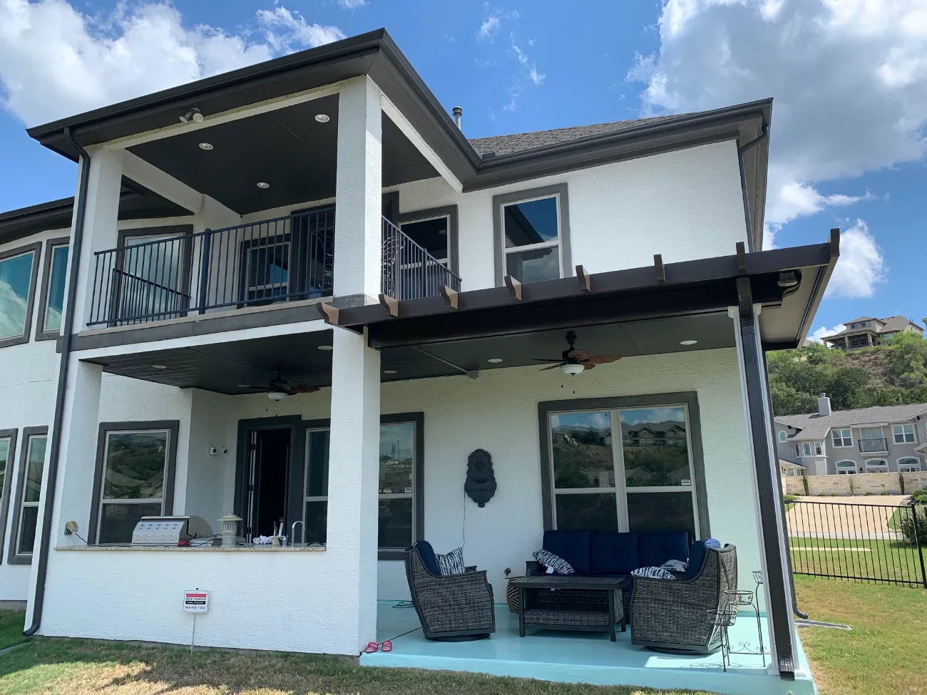 a black patio cover adjacent to a black and white two-story balcony in san antonio