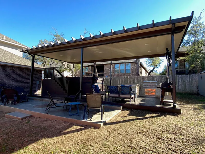 Covered outdoor patio with seating, barbecue grill, and wooden deck in a suburban backyard.
