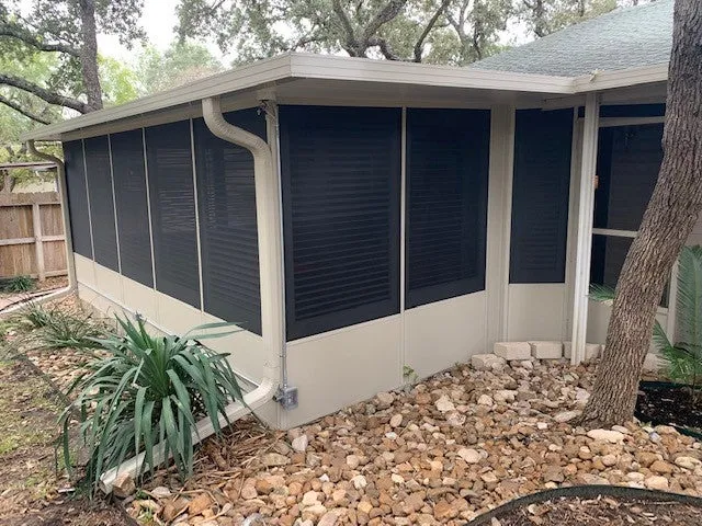 Patio enclosure with screened windows in a backyard.