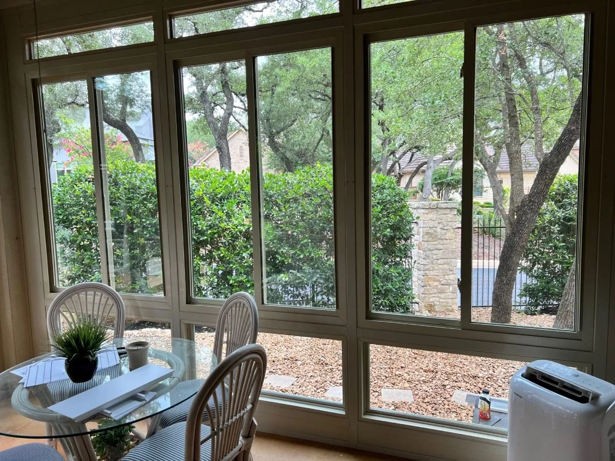 Patio enclosure with glass windows and trees.