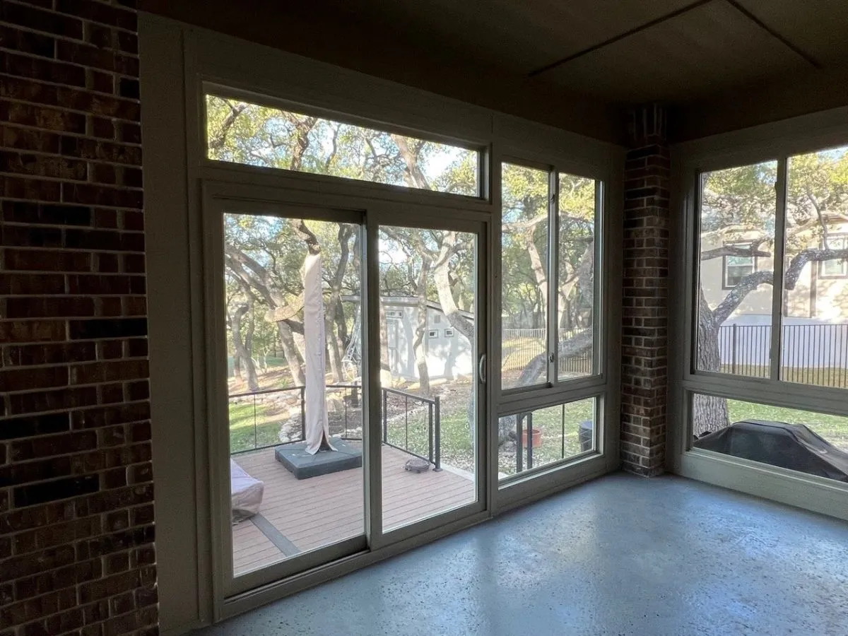 Enclosed patio with large windows and a view of trees.