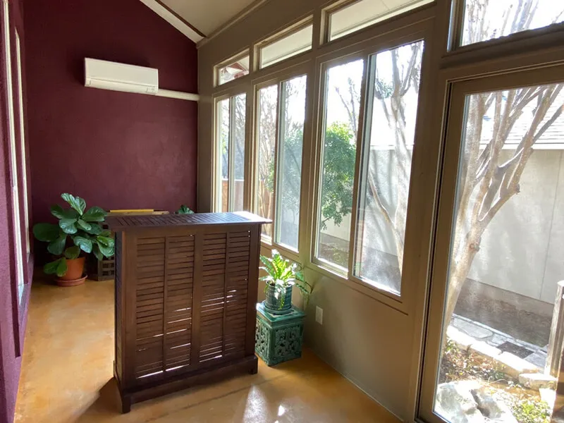 Enclosed patio in San Antonio home with large windows and plants.