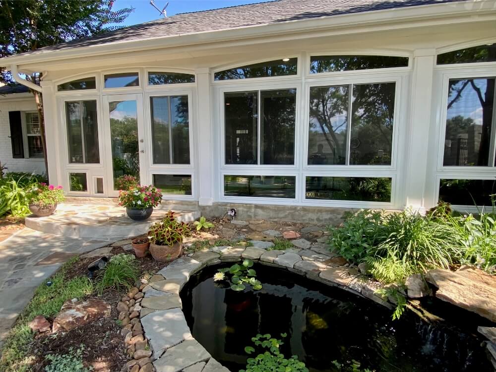 Backyard sunroom extension with pond and gardens.