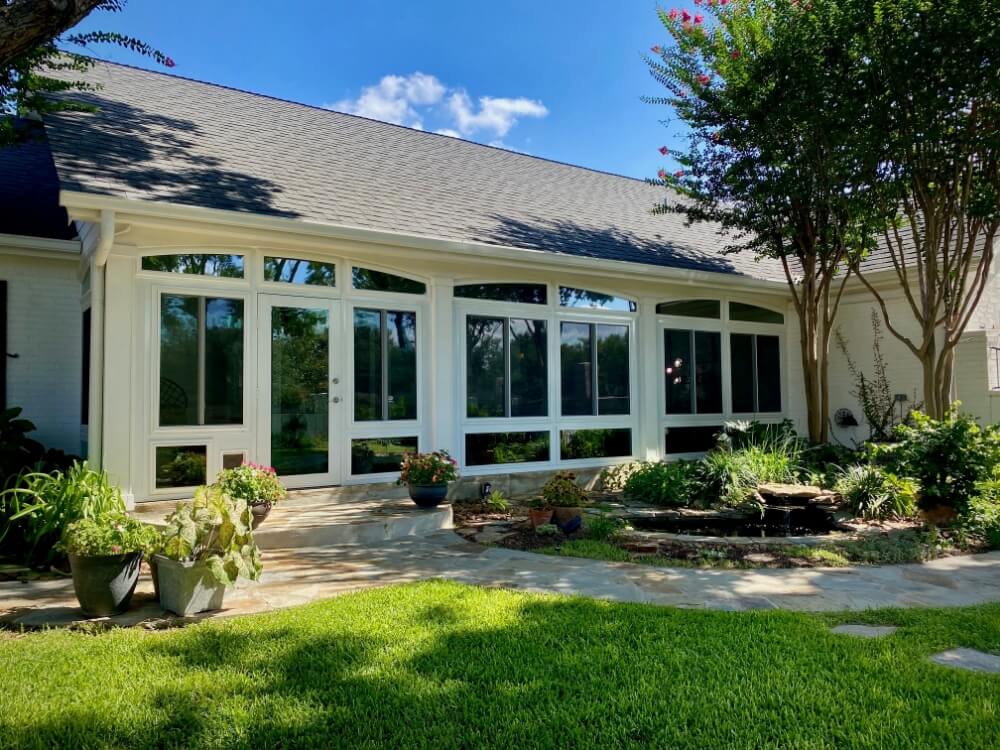 Sunroom exterior with large windows and lush garden.