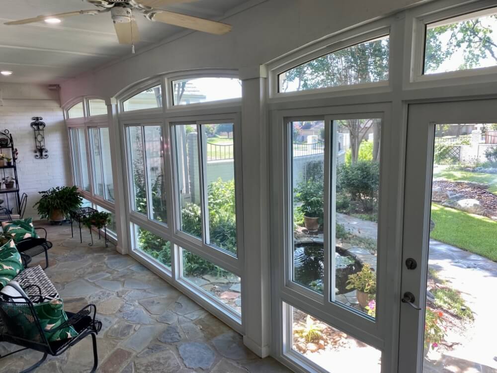 Sunroom with large windows and stone flooring.