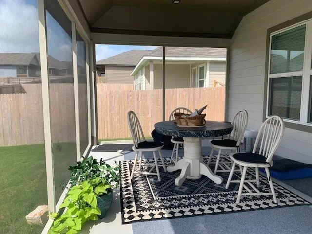 Screened-in patio with table and chairs.