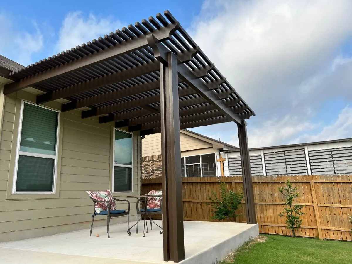 Wooden pergola over patio with chairs in backyard.