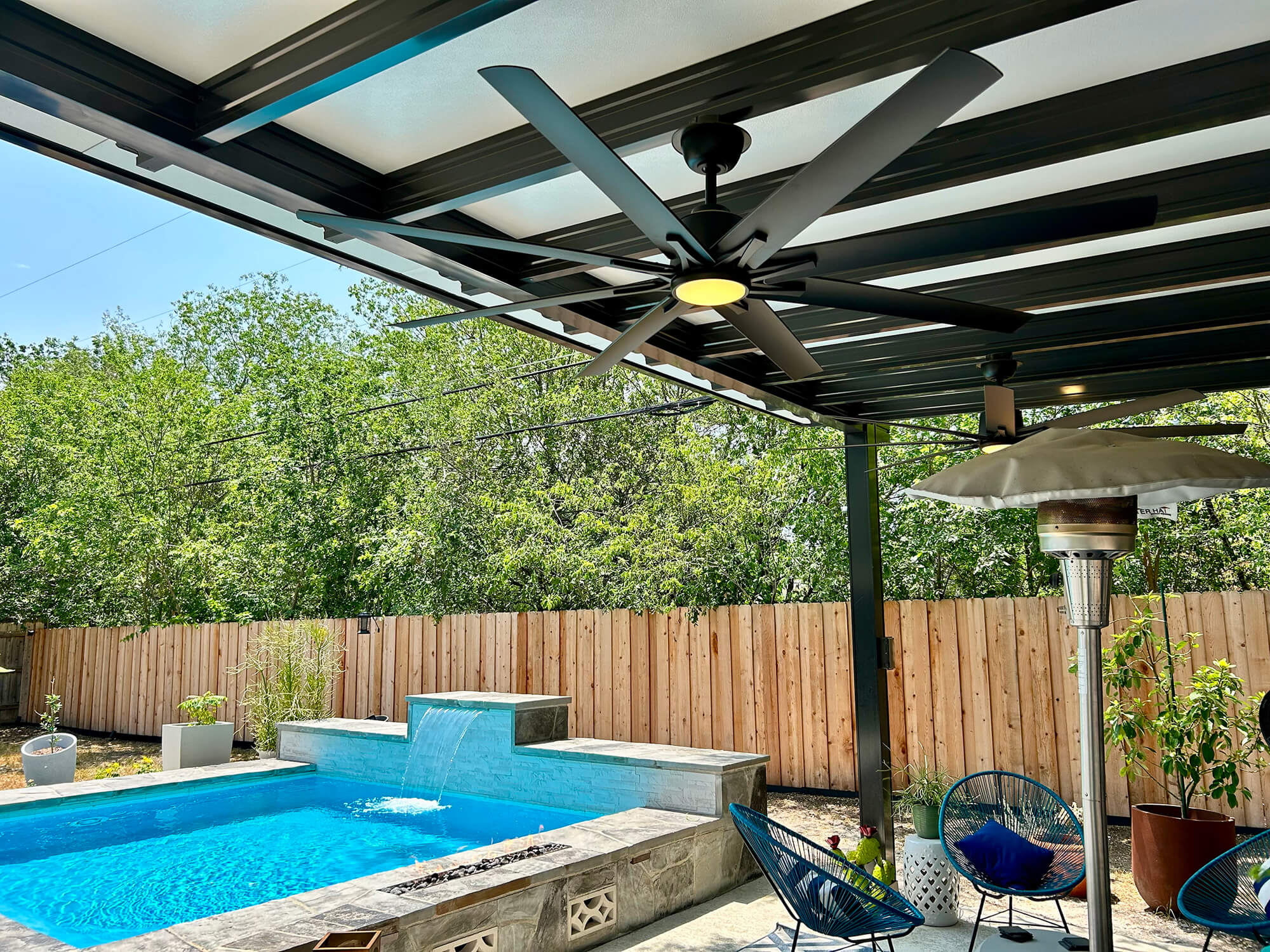 Outdoor patio with partial pergola, ceiling fan, pool, and plants.