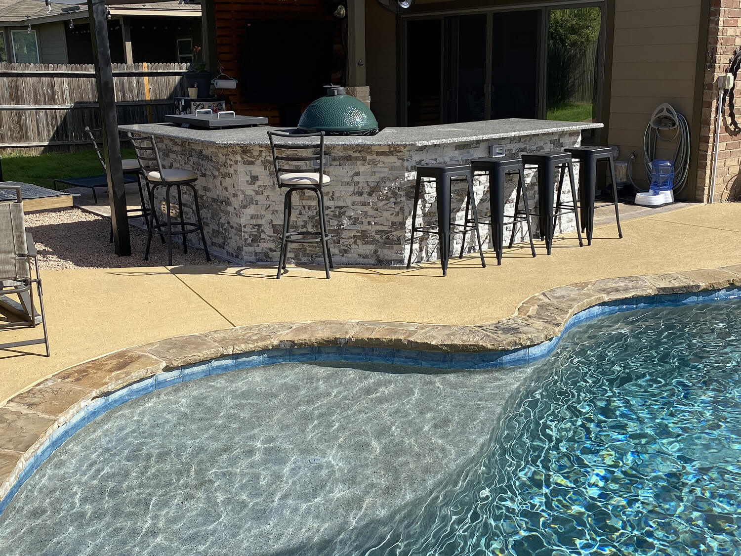 Outdoor kitchen with bar seating by a pool