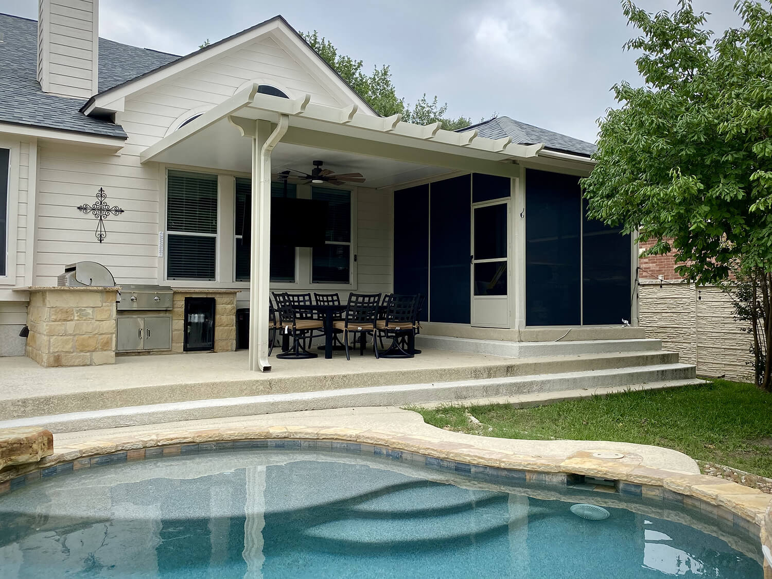 Backyard patio with pergola, outdoor kitchen, dining set, and pool in San Antonio.