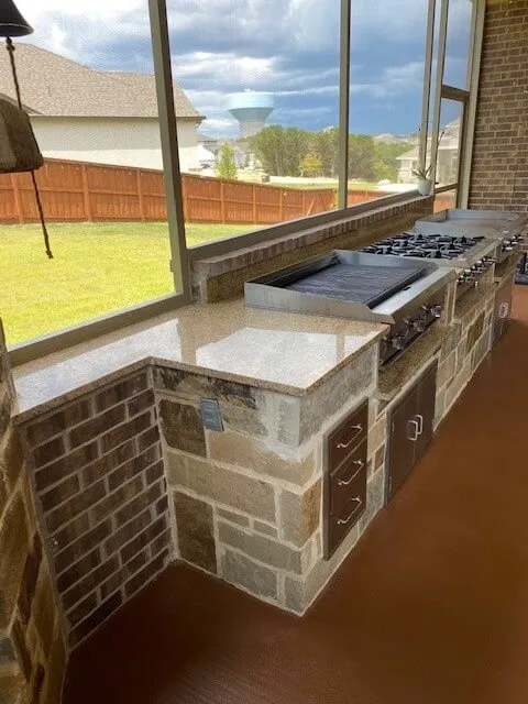 Outdoor kitchen with stone countertops and grills.