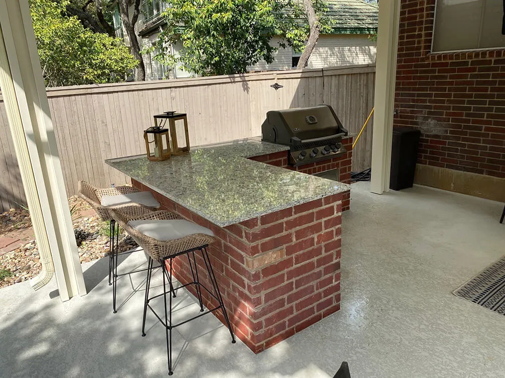 Outdoor kitchen with brick island and grill in San Antonio patio.