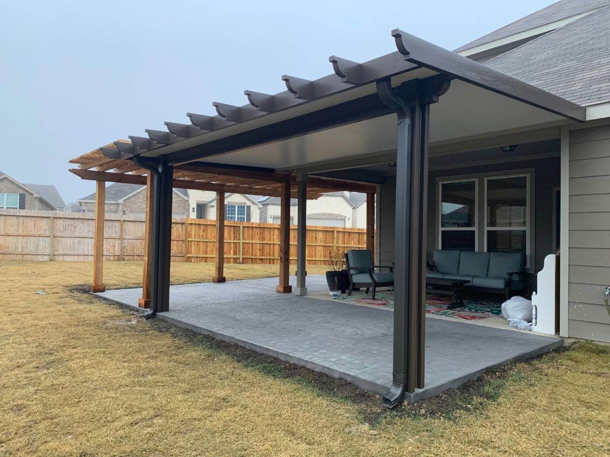 a large black patio cover with concrete slab flooring adjacent to wooden pergola in san antonio