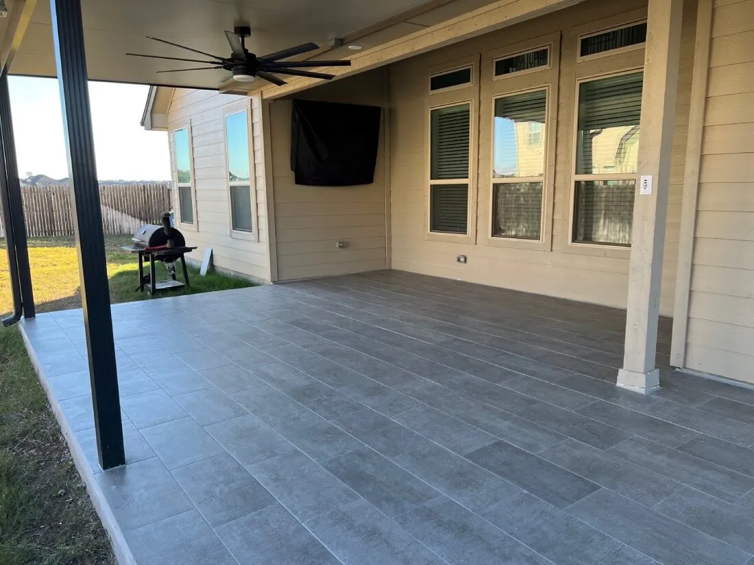 Covered patio with ceiling fan and tiled floor in San Antonio backyard.