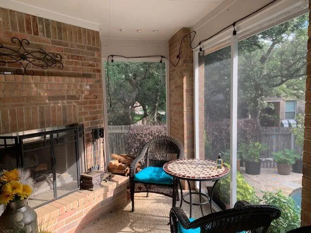 Screened patio with a table, chairs, and fireplace.