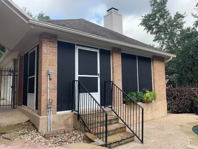 Screened patio enclosure attached to brick house.