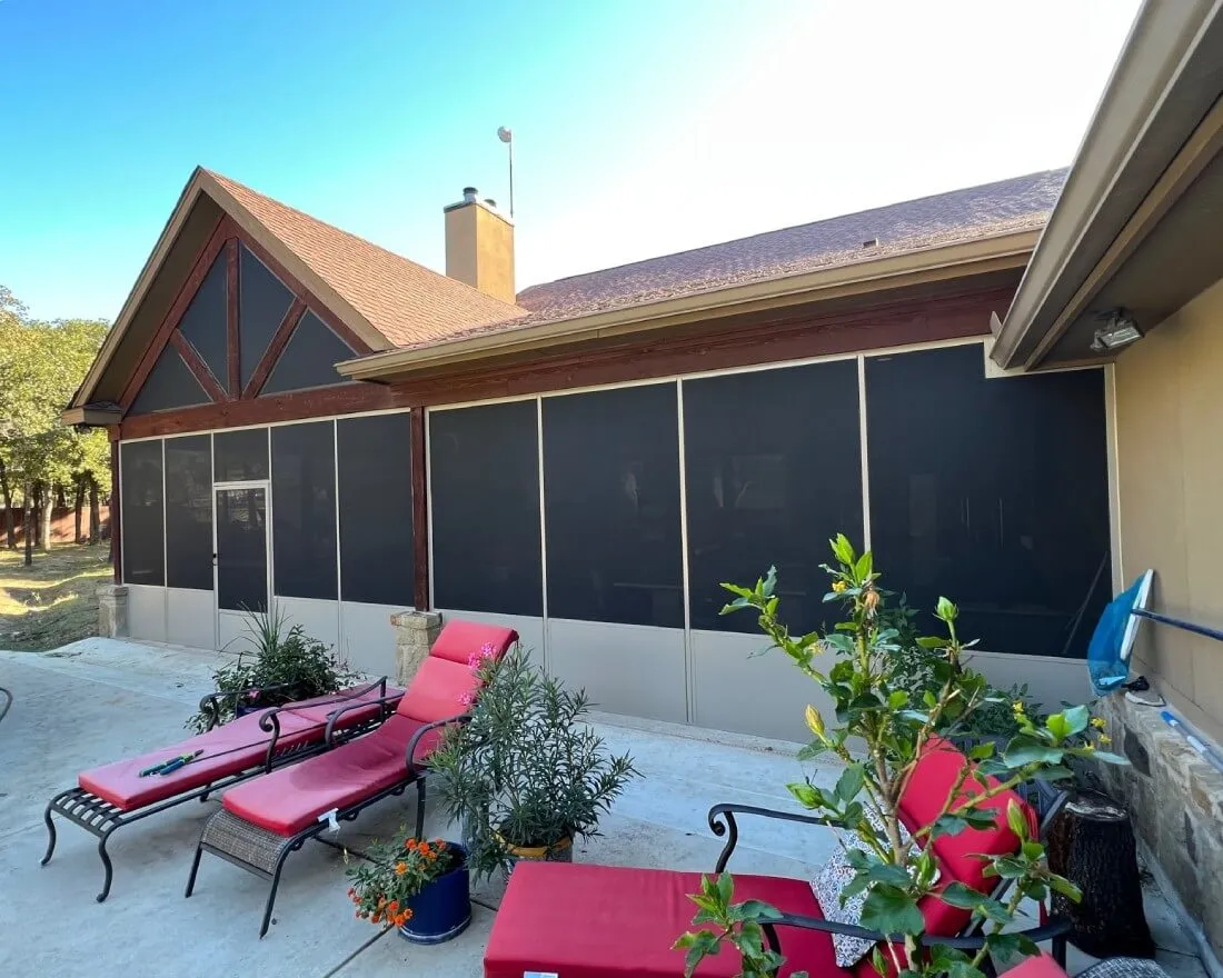 Screened patio enclosure with red lounge chairs.