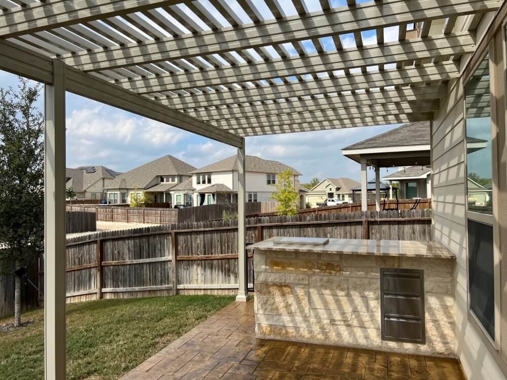 Pergola over patio with outdoor kitchen in San Antonio backyard.