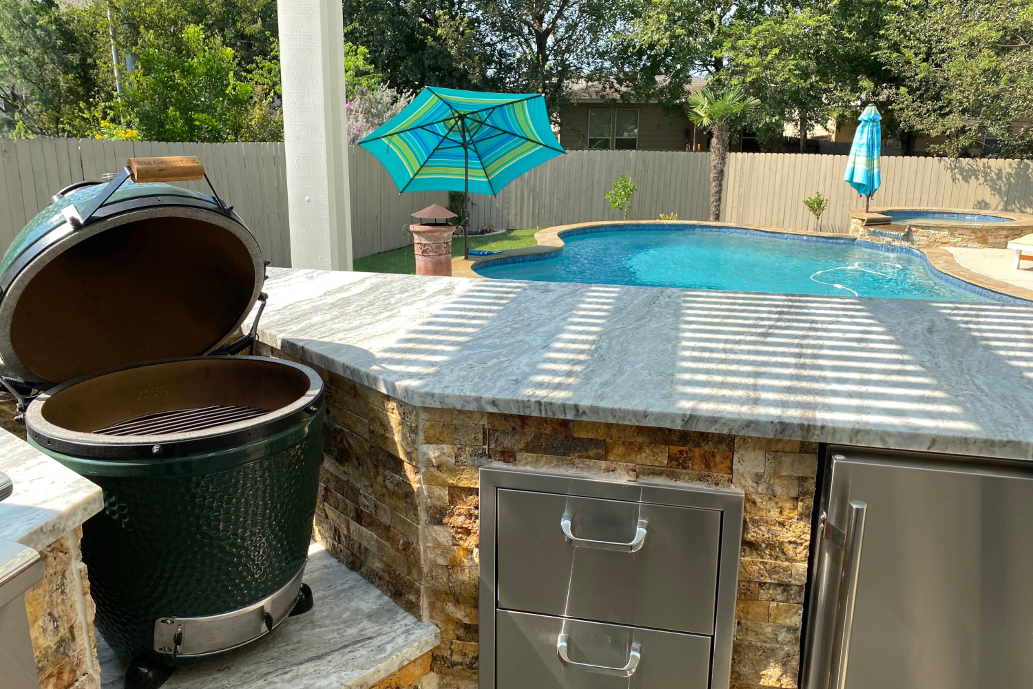 Outdoor kitchen with grill and pool view.