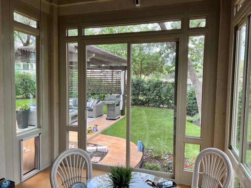 Sunroom with large windows overlooking a backyard garden in San Antonio.
