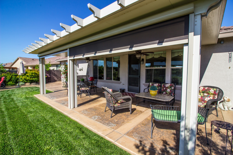 Patio cover with seating area in a sunny backyard.