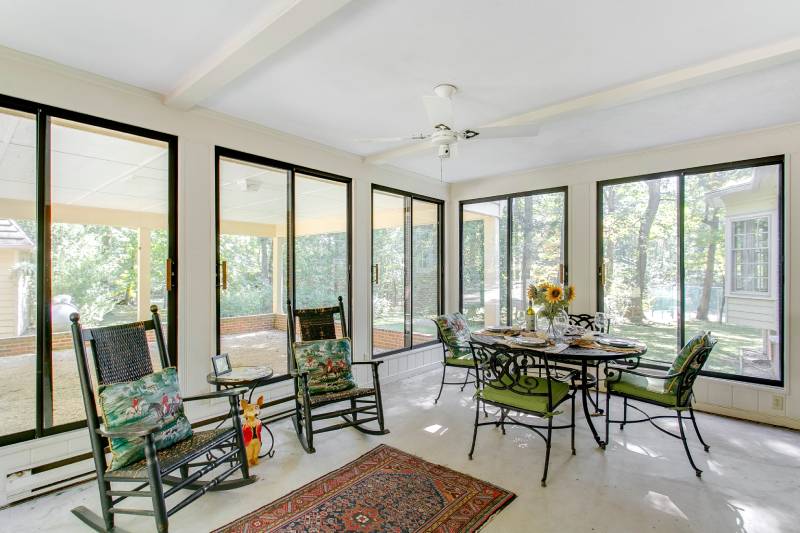 Sunroom with tables, chairs, and large windows.