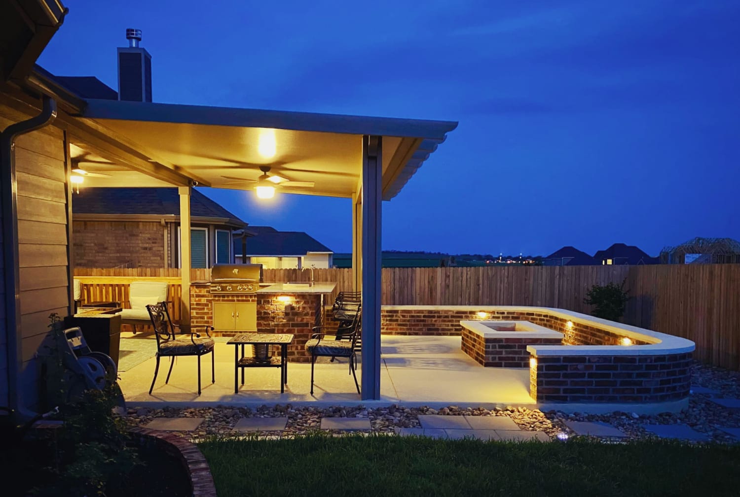Dramatic outdoor patio with grill and seating at night.