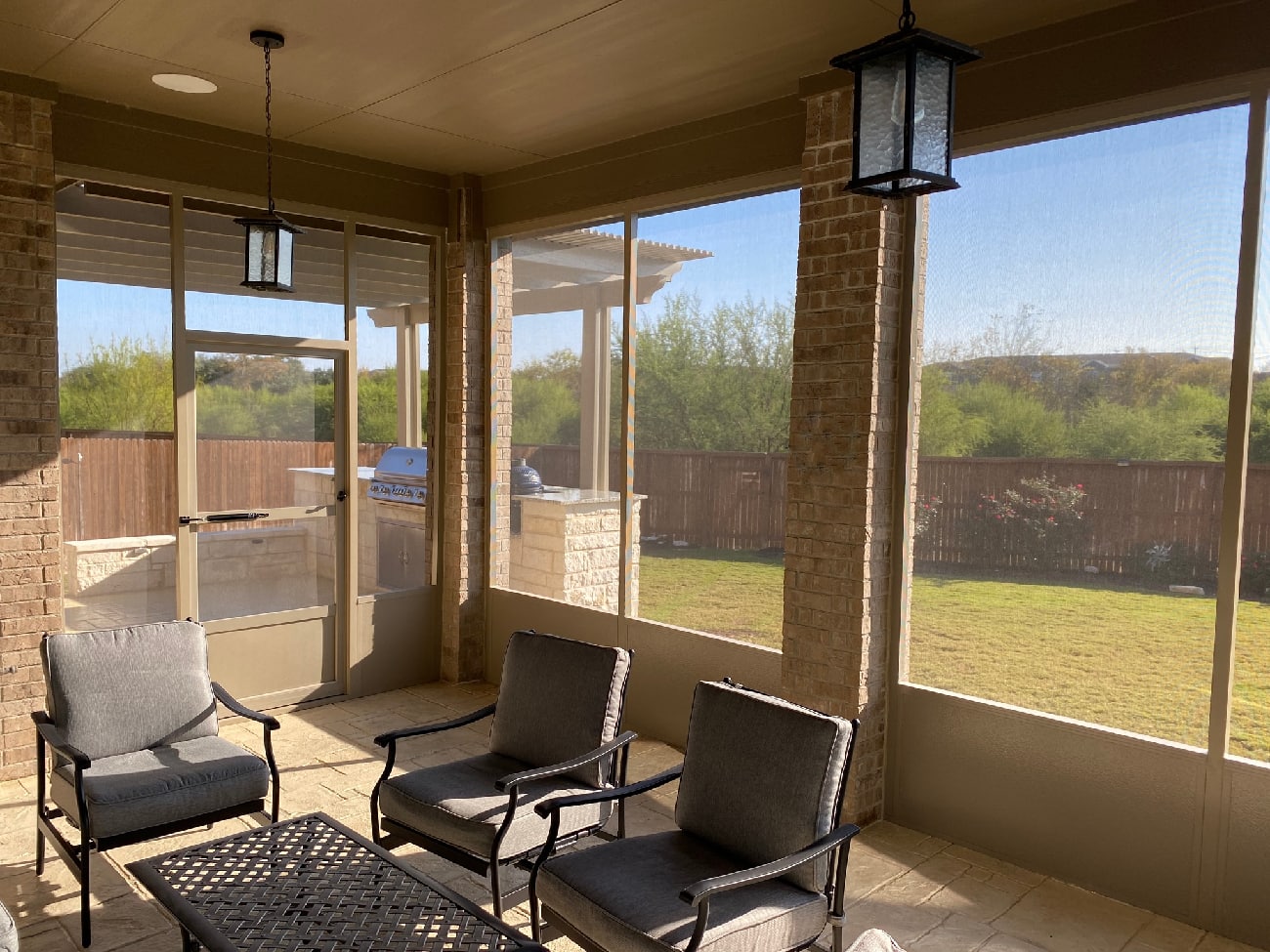 Screened-in patio with seating and outdoor view.
