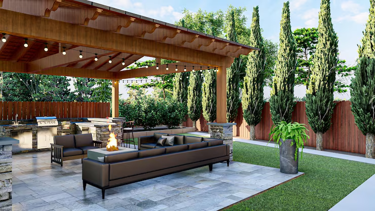 Covered outdoor patio with modern seating, a fire pit, greenery, and tall trees.