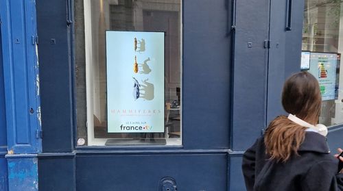 jeune femme passant devant un écran pour France TV _ mammifères