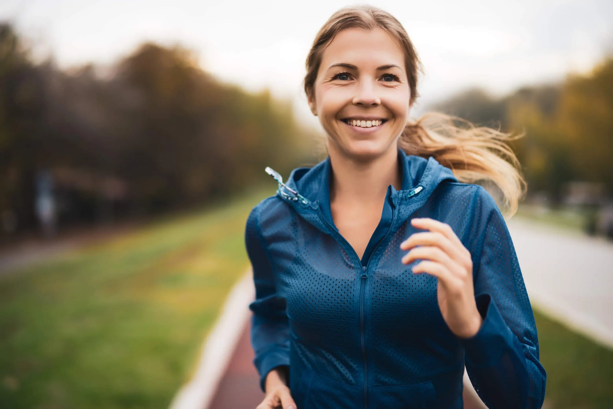 Healthy happy woman jogging outdoors on a cloudy day in autumn.