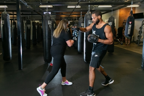A woman sparring with a male trainer