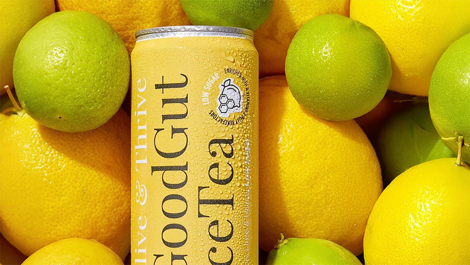 Chilled yellow can of GoodGut iced tea surrounded by fresh lemons and limes.